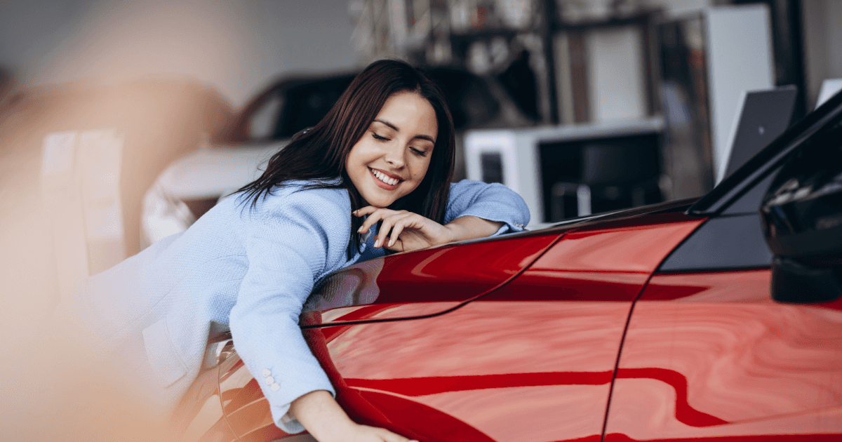 Smiling woman hugging the hood of her red Toyota