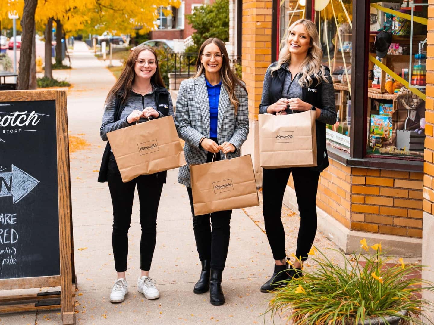 People holding bags of toys outside of Hopscotch toy store