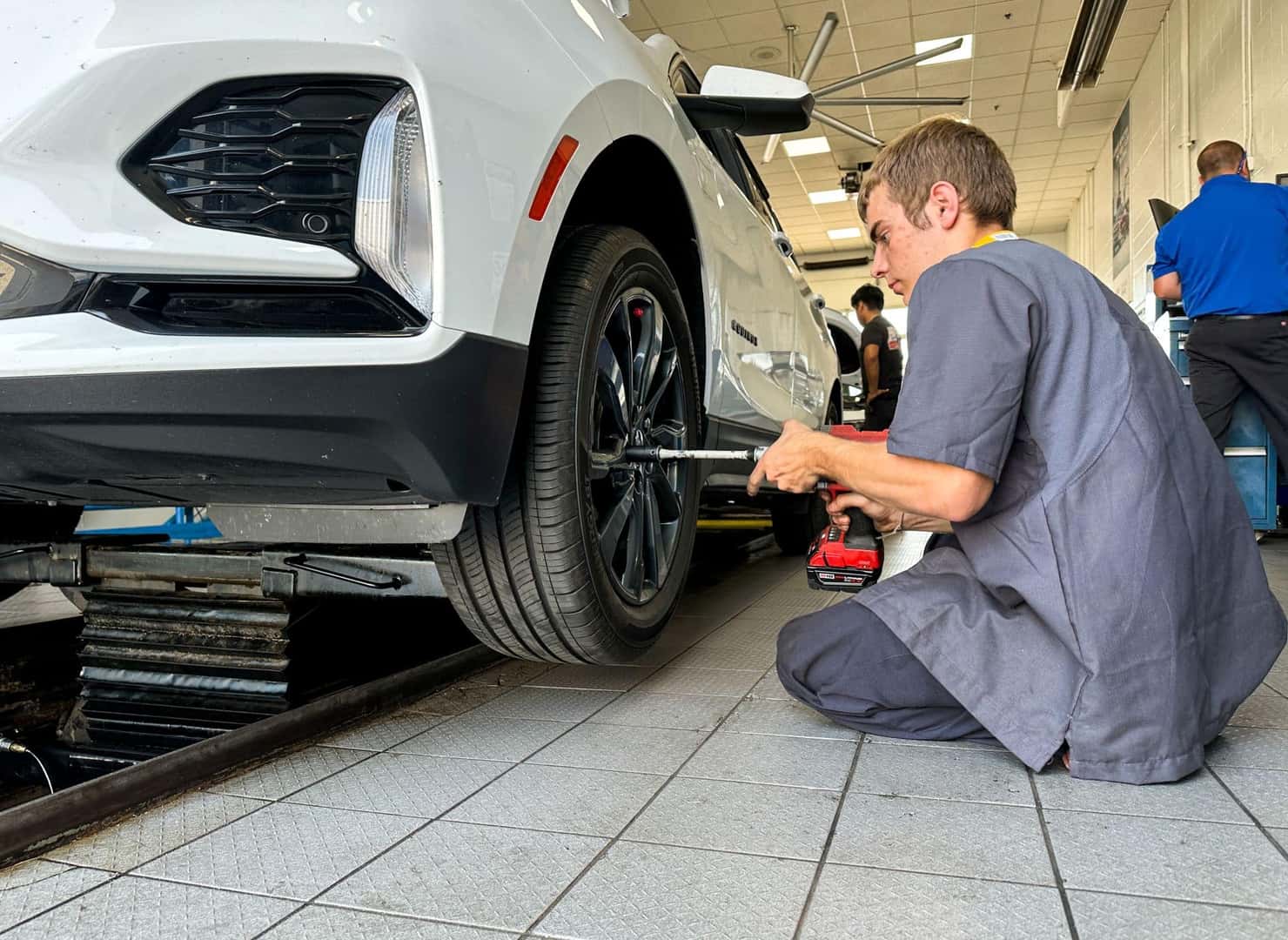 Man putting tire onto white vehicle