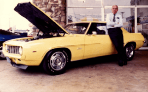 Dale Berger Jr. leaning up against a 1969 Daytona Yellow Camaro ZL1