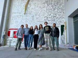 Berger employees, artist, and community members in front of the in progress Berger mural
