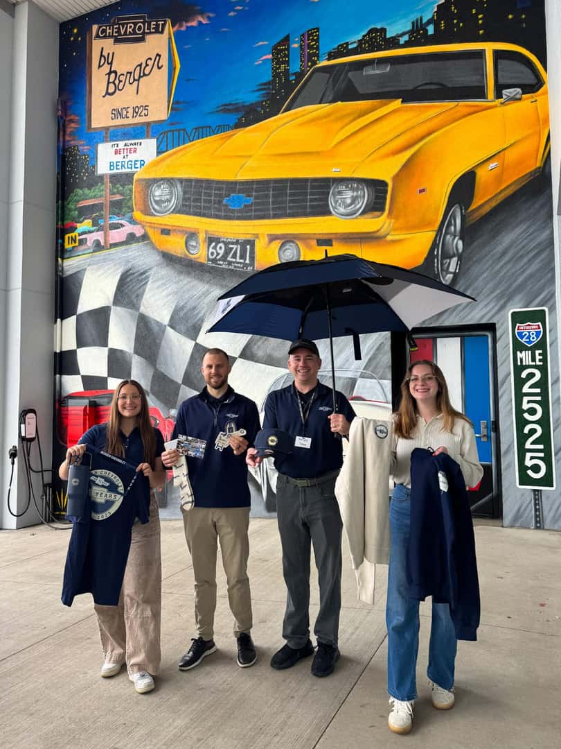 Berger employees holding prizes in front of the mural