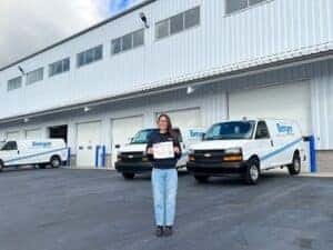 Rachel with her Employee Spotlight Certificate in front of the Parts Warehouse