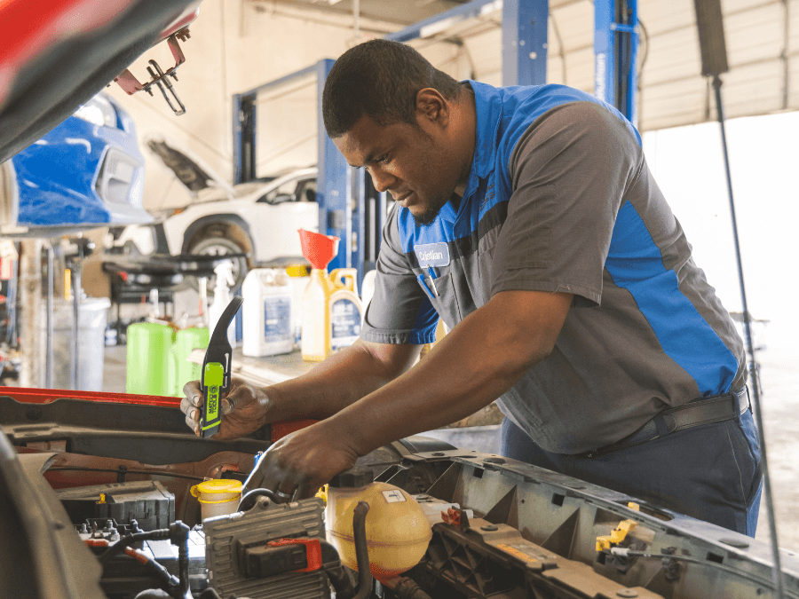 Service Tech is inspecting vehicle under the hood.
