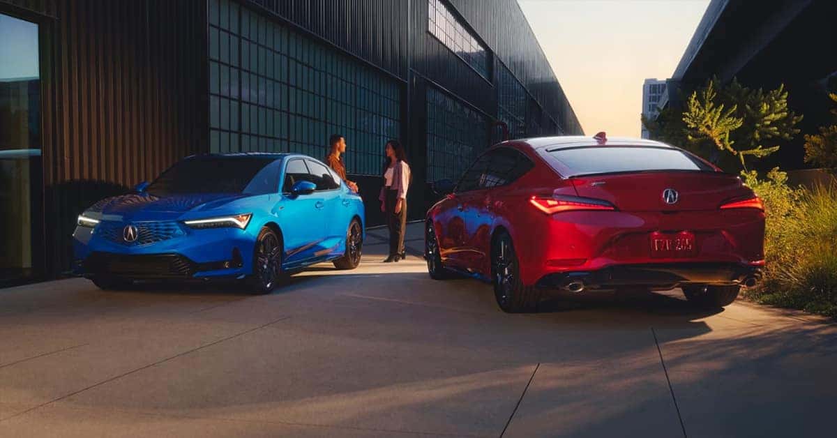 A man and a woman talk besidea blue and red Acura Integra