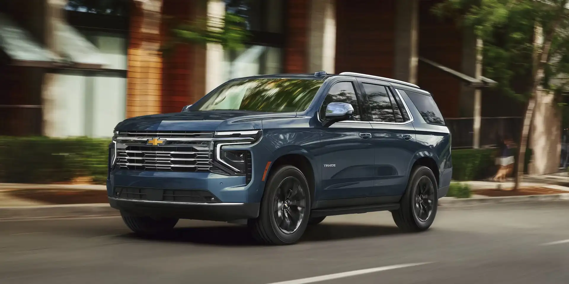 Chevrolet SUV driving on a city street at dusk