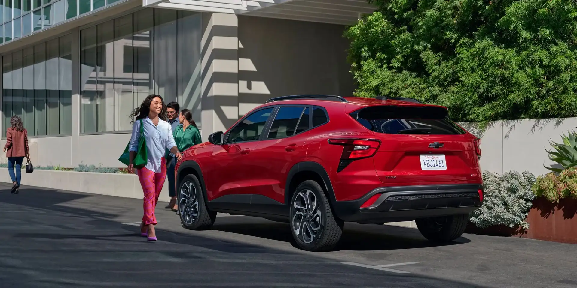 Red Chevrolet Trax parked at a kerb as two people walk past