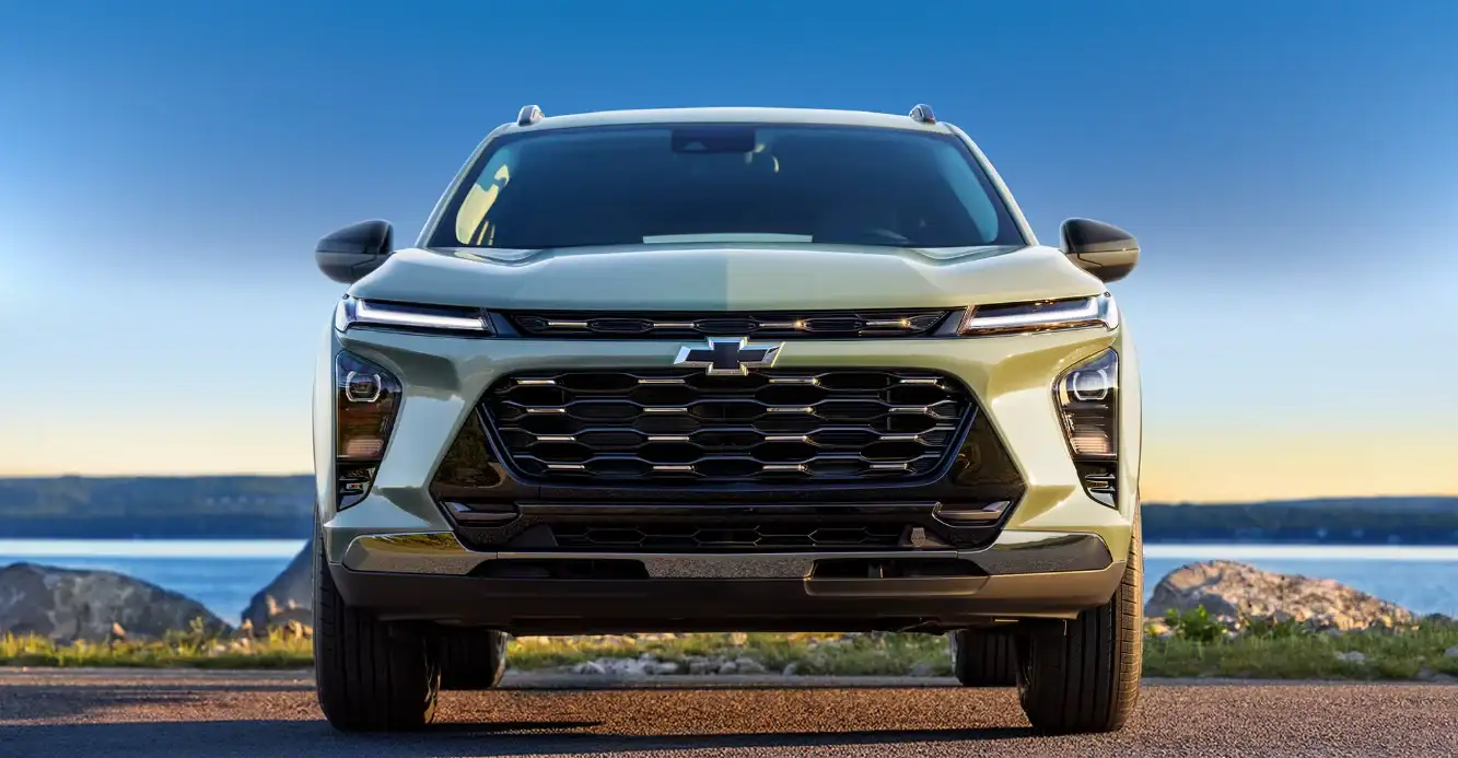 Head-on front view of a sage green Chevrolet Trax on a coastal road