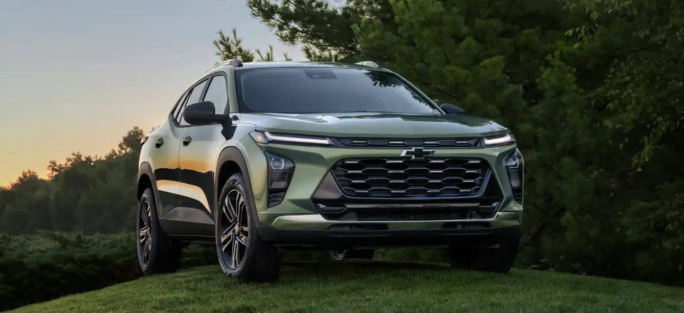 Sage green Chevrolet Trax parked among trees at dusk