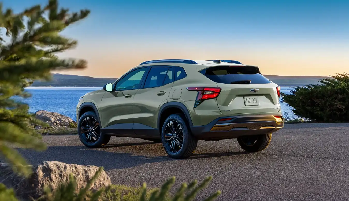 Sage green Chevrolet Trax rear three-quarter view beside a rocky coastline