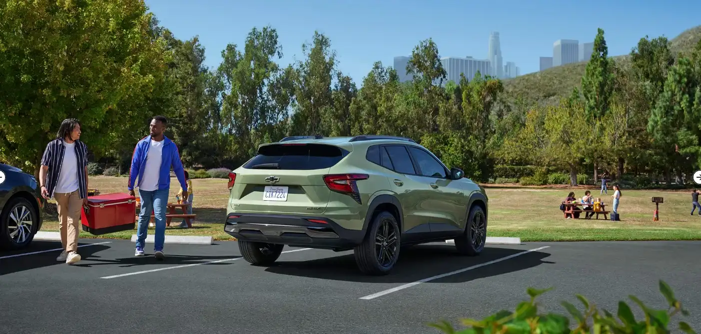 Sage green Chevrolet Trax parked in a park as two people walk toward it