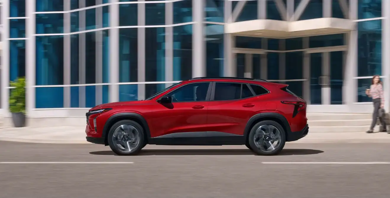 Red Chevrolet Trax side profile driving through the city