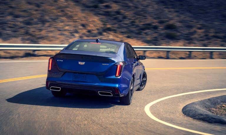 2024 Cadillac CT4 driving away on curved mountain road