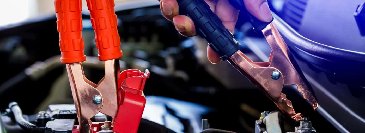 A man attaching cables to battery to jump starting a car