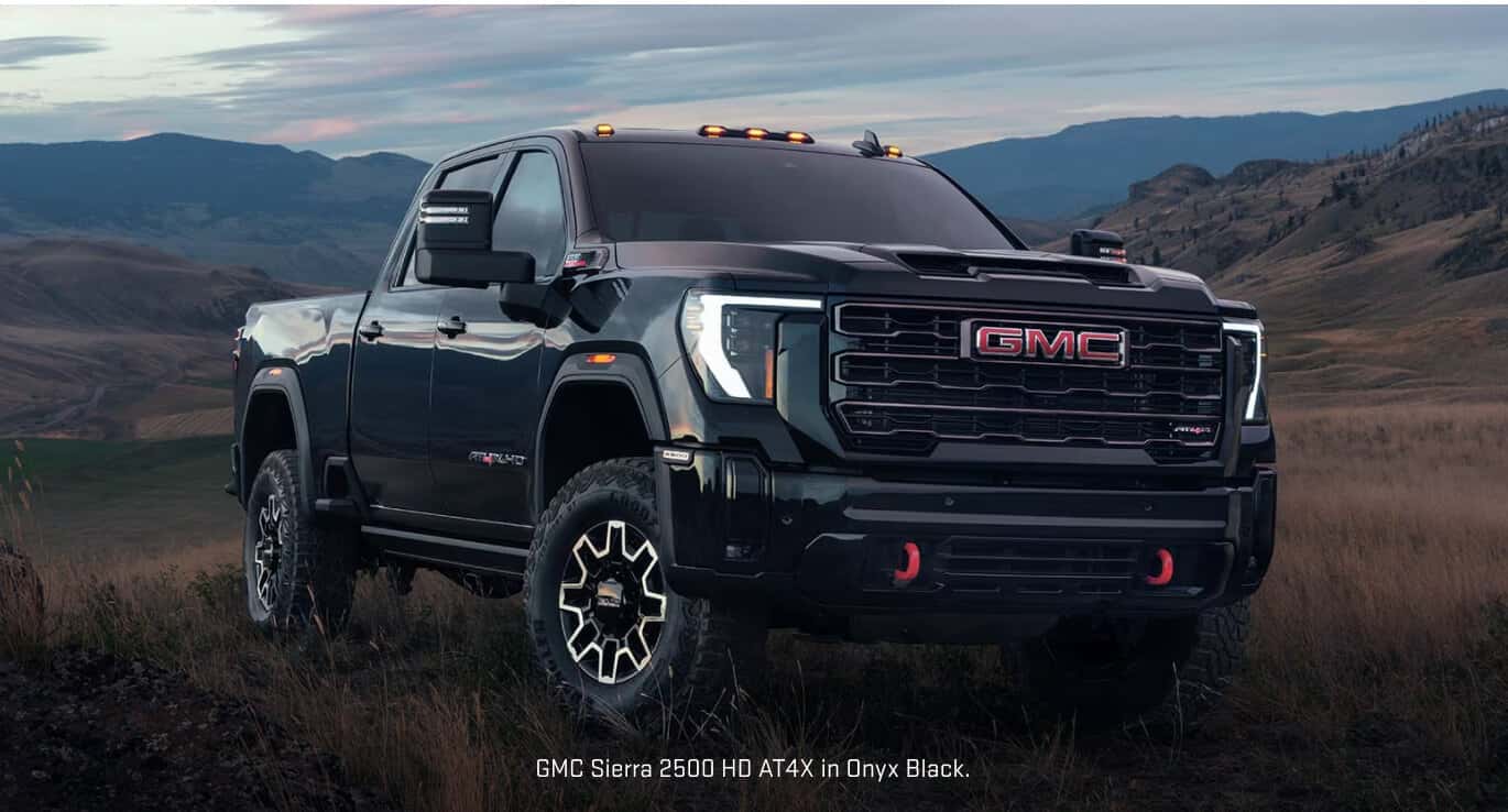 Front three-quarter view of a GMC Sierra 2500 HD AT4X in Onyx Black parked on a grassy terrain.