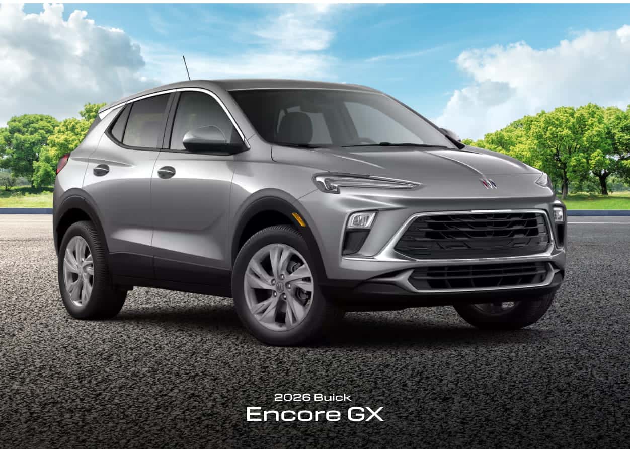 Silver 2026 Buick Encore GX parked on a textured pavement with grass and trees in the background.