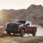 2024 GMC Sierra 2500HD AT4X driving in the desert with mountains in the background.