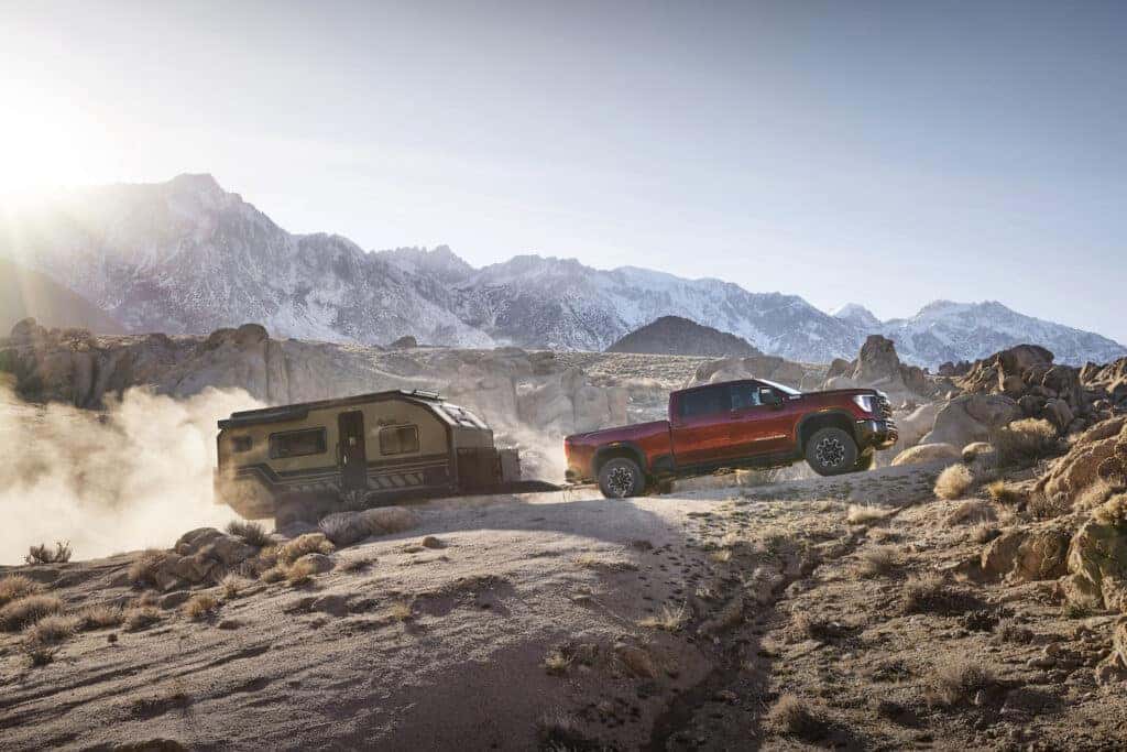 2024 GMC Sierra 2500HD AT4X towing a trailer through rocky mountain terrain.