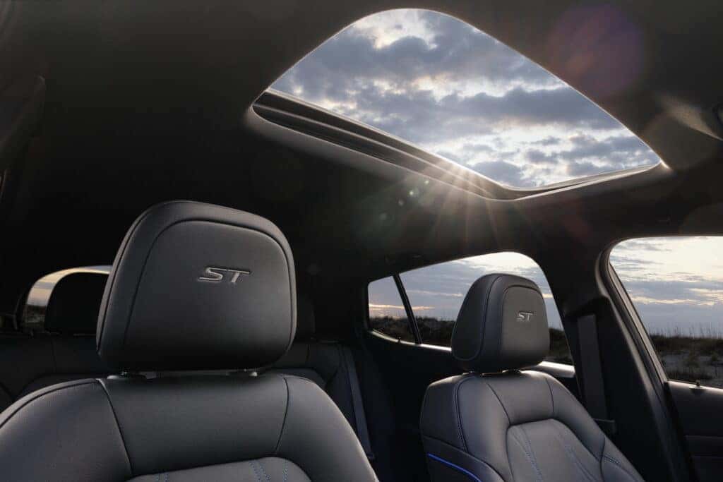 Passenger side view of 2024 Buick Envista ST front cabin showing ST logo stitching with Ebony interior and Santorini Blue accents. Preproduction model shown. Actual production model may vary. Available in summer 2023.