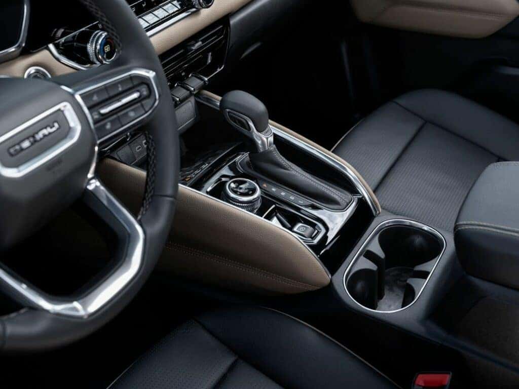 Detail view of GMC Canyon Denali center console with gear shifter and cupholders.