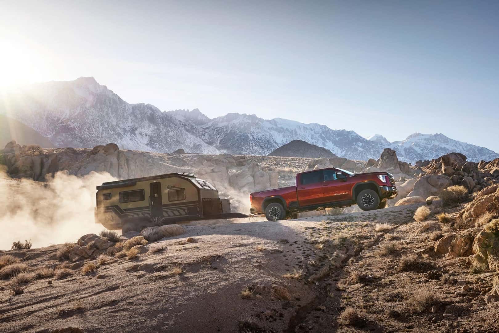 A Scarlet 2024 GMC Sierra Driving Up A Hill, Towing A Heavy Haul