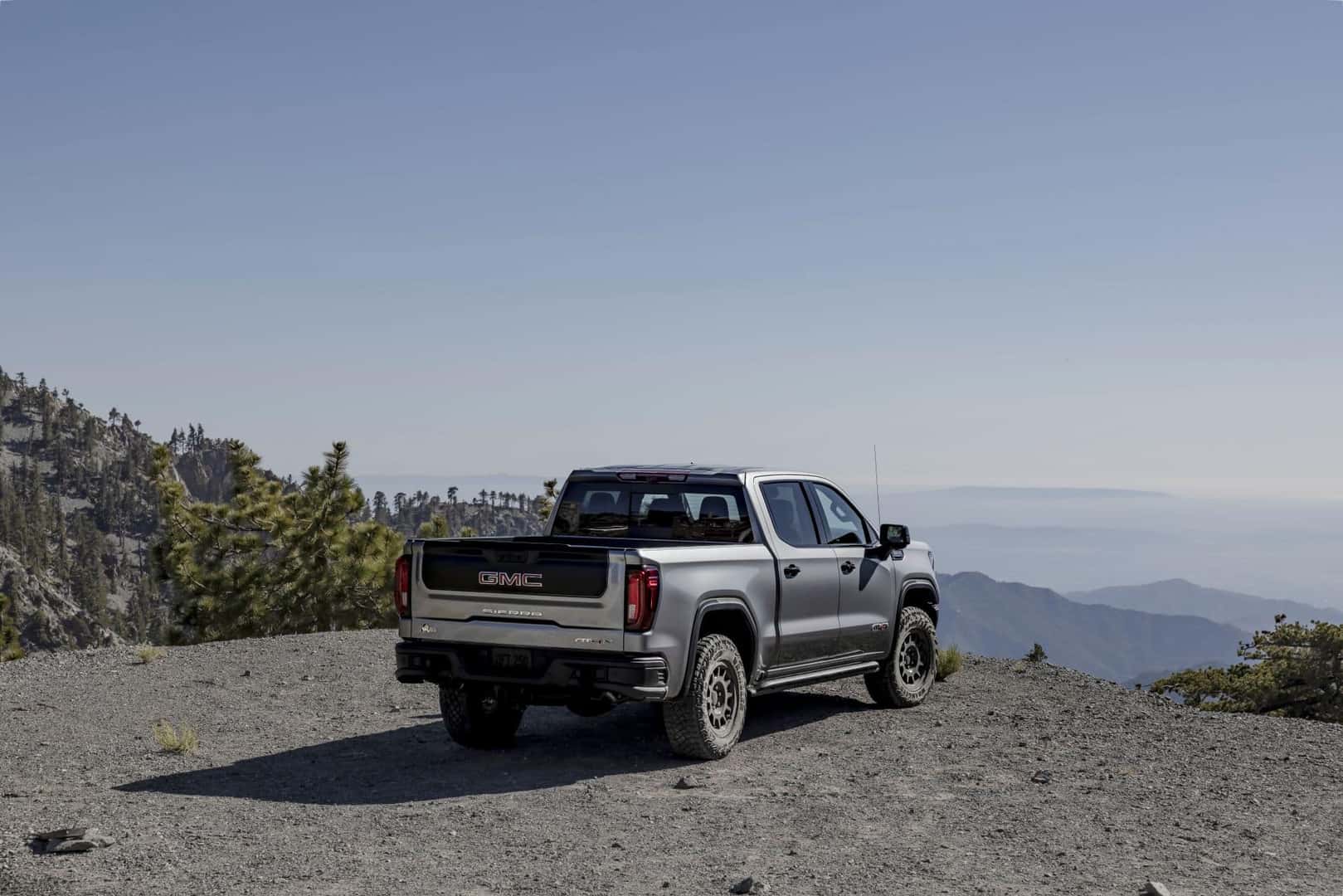 A Fierce 2024 GMC Sierra AT4X AEV Overlooking From A Mountain Cliff