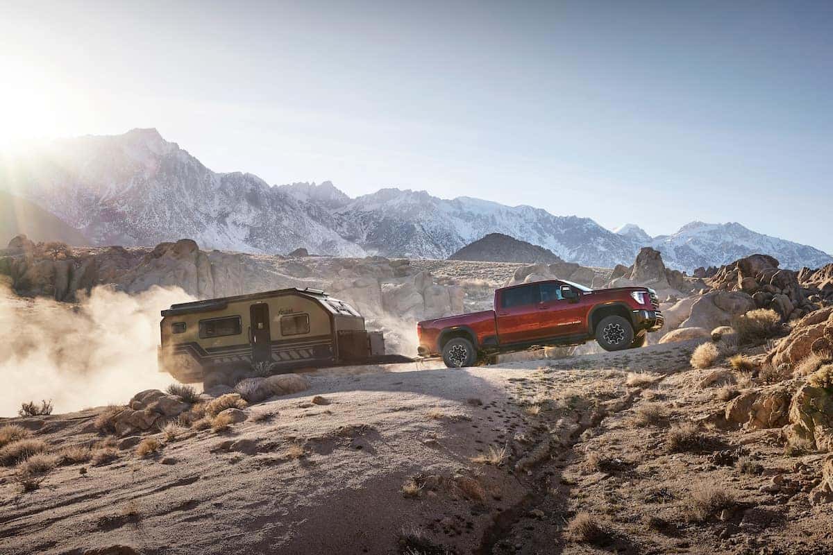 2024 GMC Sierra 2500HD AT4X towing a trailer through rocky mountain terrain.