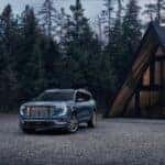 The 2024 GMC Acadia Denali Parked Outside A Forest Cabin