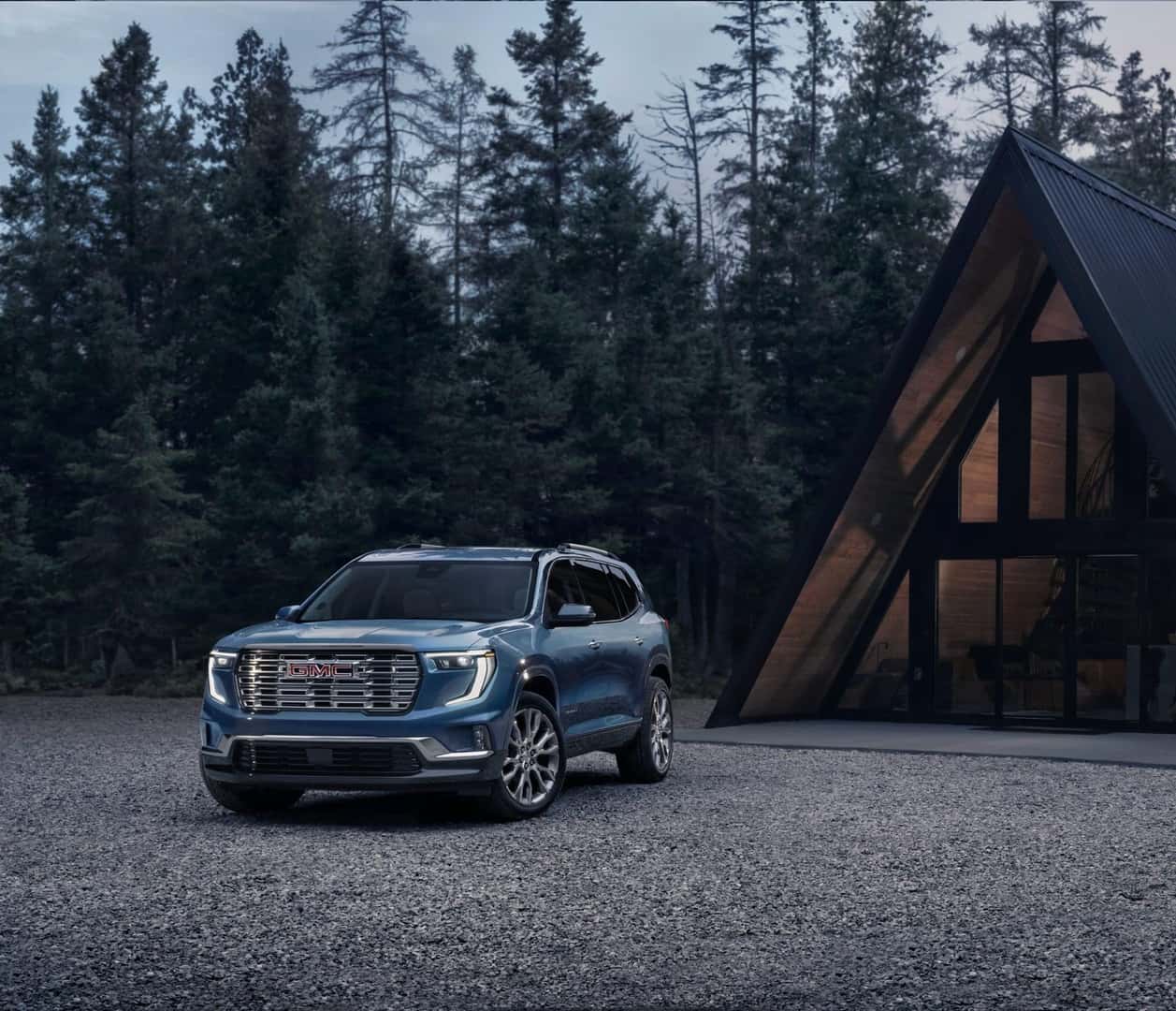The 2024 GMC Acadia Denali Parked Outside A Forest Cabin