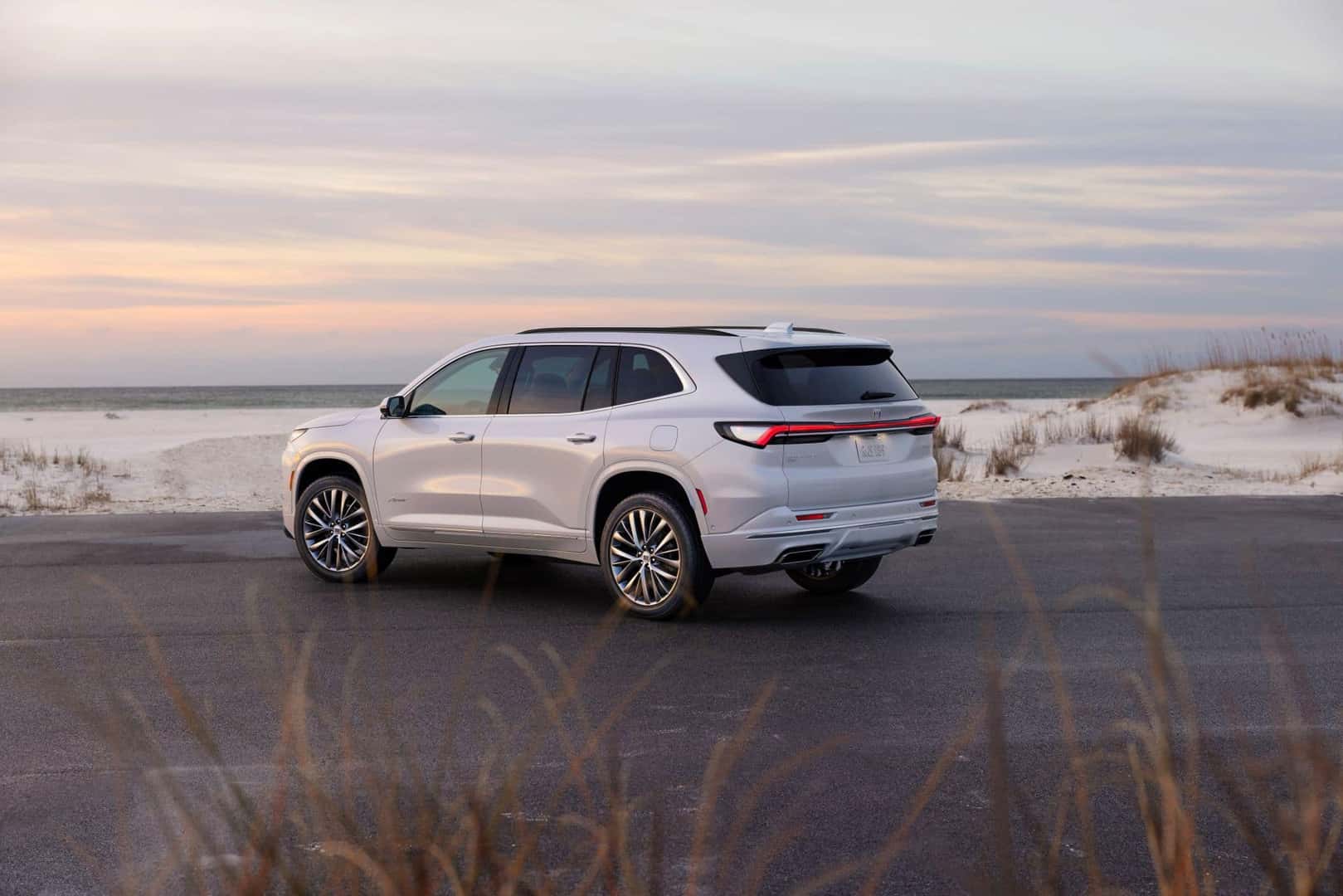 The 2025 Buick Enclave Avenir's Beautiful Back Exterior, Parked At The Edge Of A Pale Beach