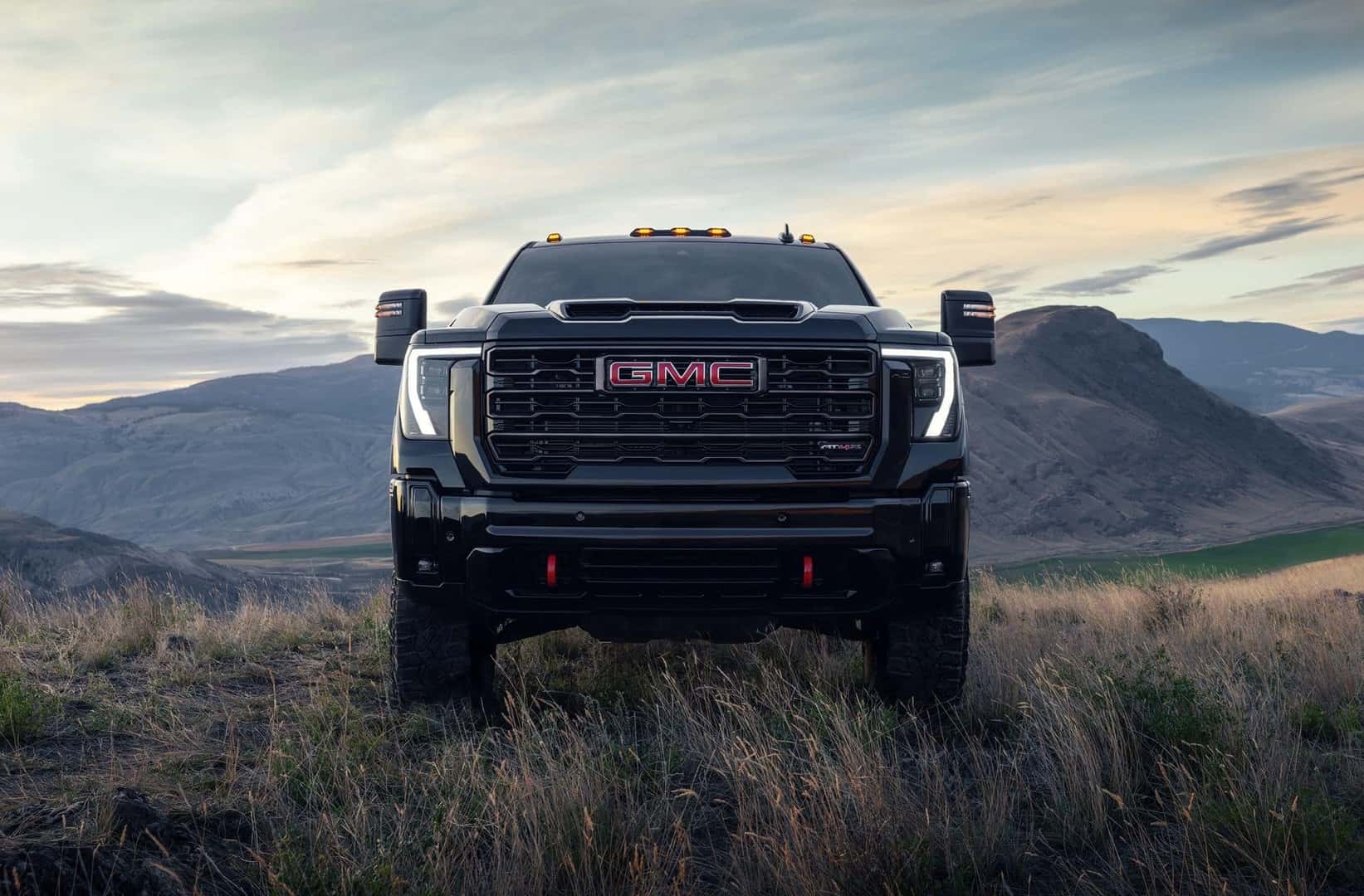 The Ultimate Heavy-Duty Pickup Truck: The 2026 GMC Sierra 2500, Intimidatingly Parked In The Grass, With Huge Mountains In The Background
