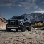 Front view of GMC Yukon Denali Ultimate parked off road in front of mountains