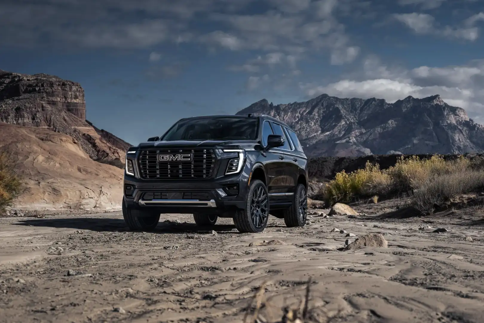 Front view of GMC Yukon Denali Ultimate parked off road in front of mountains