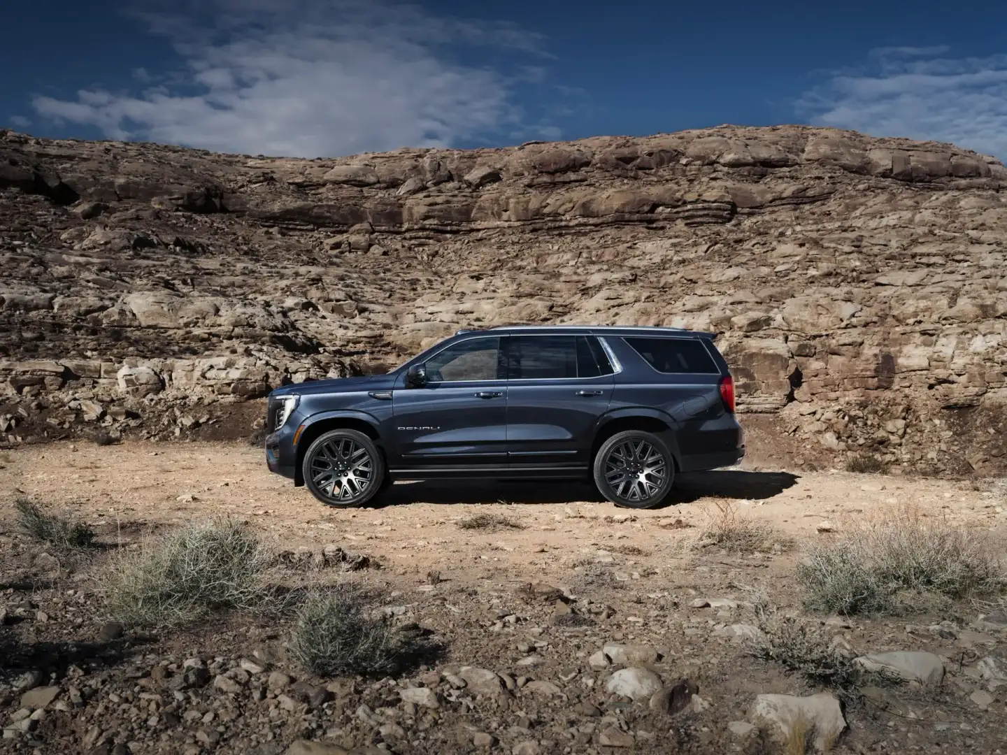 Side view of GMC Yukon Denali Ultimate parked off road on a rocky mountain