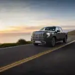 2026 GMC Sierra Denali Ultimate driving on a road at sunset