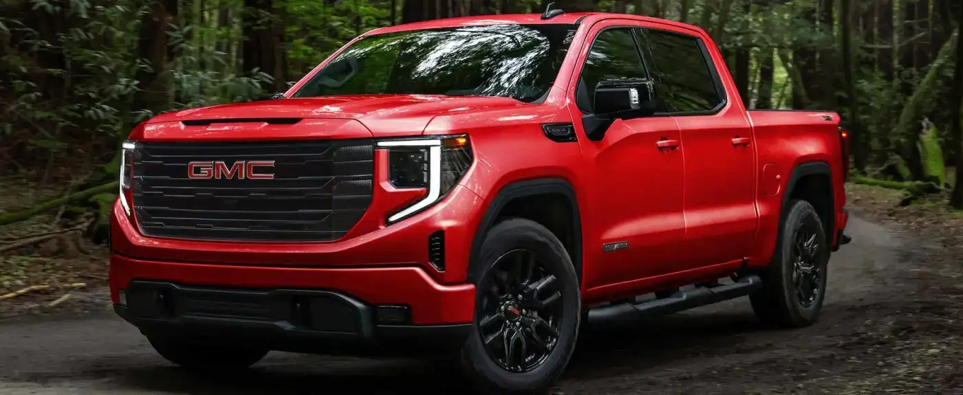Red GMC Sierra parked off road in nature
