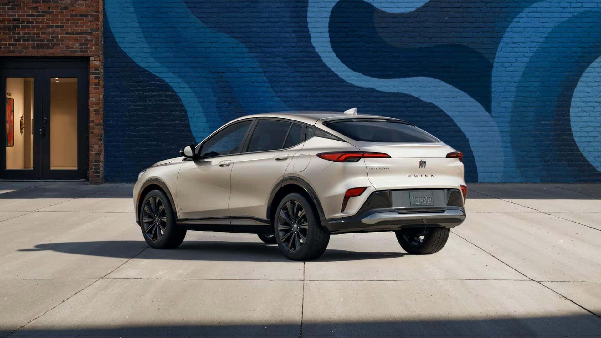 The Stylish Back Exterior Of The Inexpensive And Reliable 2026 Buick Envista, Parked In Front A Brick Building With A Large, Gorgeous Mural