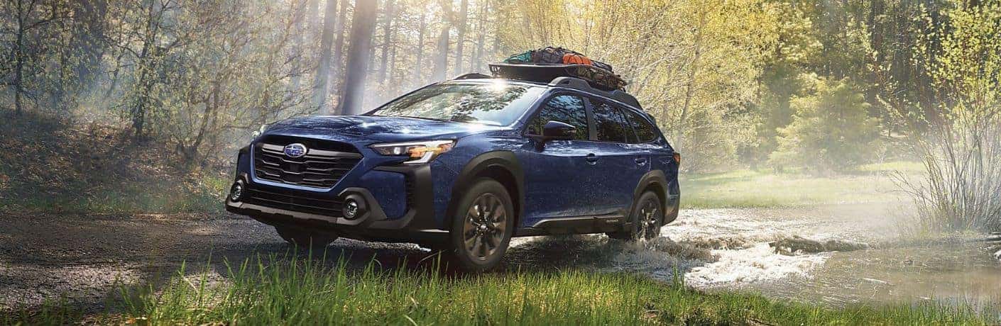 Blue 2023 Subaru Outback with Cargo on a Wooded Trail
