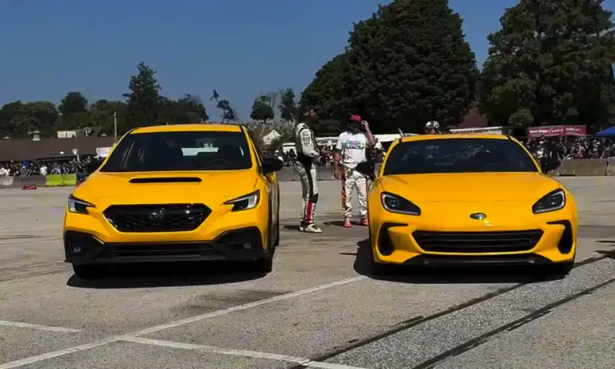 2026 yellow WRX and BRZ parked side by side in a parking lot with Subaru lovers admiring them