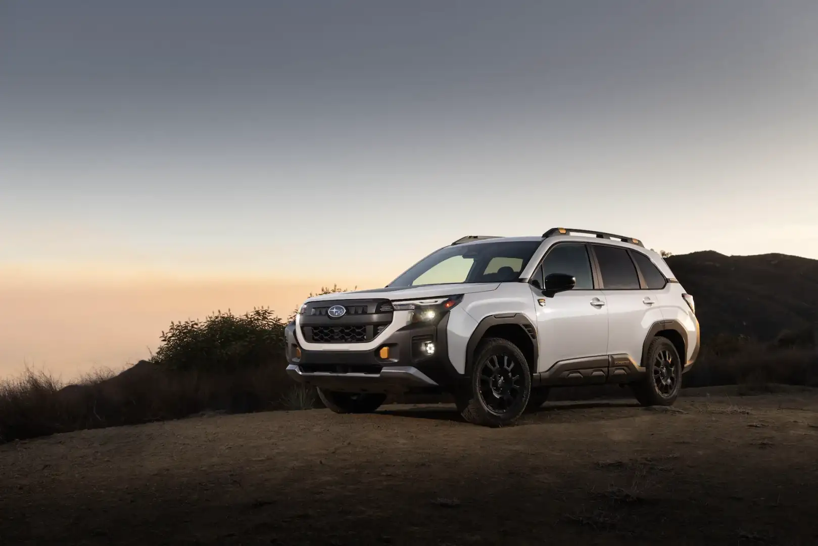 2026 Subaru Forester Wilderness view of the front parked on grass in front of a lake at sundown