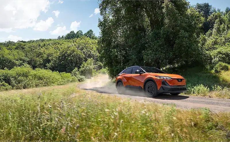 2026 Subaru Uncharted driving around a tree bend on a gravel road