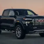 2026 GMC Canyon Denali near Ruth NC in gloss black with chrome GMC grille, Denali badging, at sunset
