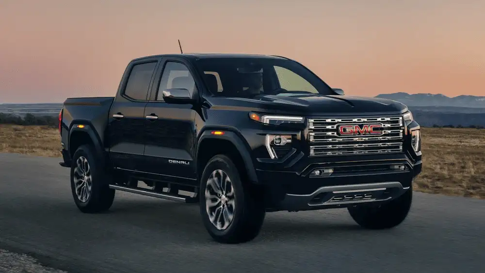 2026 GMC Canyon Denali near Ruth NC in gloss black with chrome GMC grille, Denali badging, at sunset