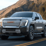 2026 GMC Sierra EV Denali near Ruth NC in gray with red GMC grille lettering and LED headlights on a coastal highway