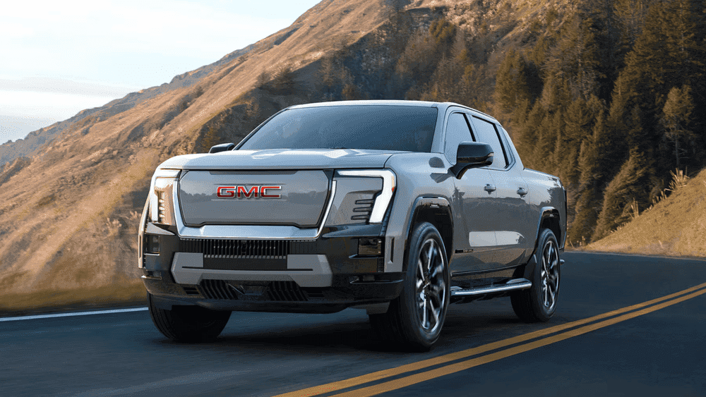 2026 GMC Sierra EV Denali near Ruth NC in gray with red GMC grille lettering and LED headlights on a coastal highway