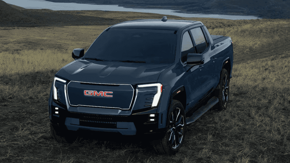 2026 GMC Sierra EV Denali near Ruth NC in dark blue with red GMC grille lettering and LED headlights on a grassy hill