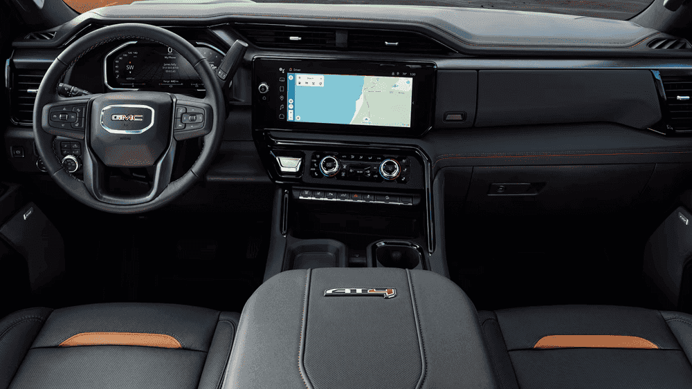 2026 GMC Sierra Heavy Duty AT4 dashboard near Ruth NC with GMC steering wheel, touchscreen Maps, and orange accent seats