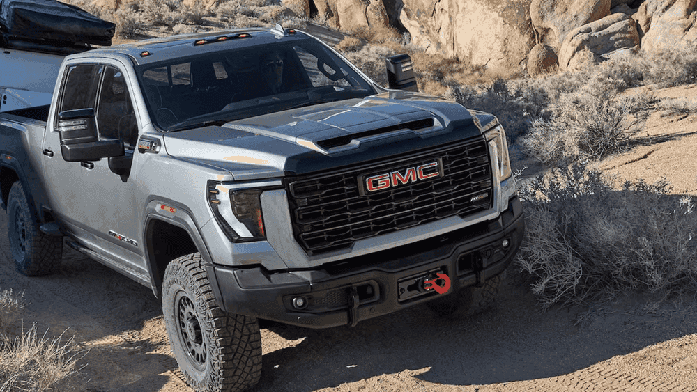 2026 GMC Sierra Heavy Duty near Ruth NC in silver AT4X with GMC grille, winch, and off-road tires on rocky terrain
