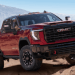 2026 GMC Sierra Heavy Duty AT4X near Ruth NC in red with GMC grille, off-road tires, and red tow hooks on rocky terrain