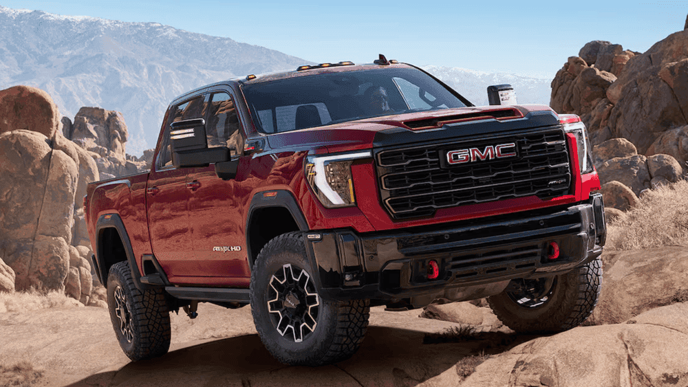 2026 GMC Sierra Heavy Duty AT4X near Ruth NC in red with GMC grille, off-road tires, and red tow hooks on rocky terrain
